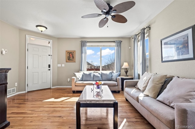 living area featuring ceiling fan, visible vents, baseboards, and light wood-style flooring