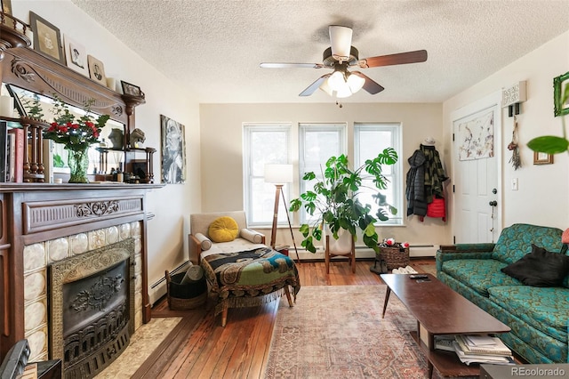 living room featuring a baseboard heating unit, a fireplace, a textured ceiling, ceiling fan, and hardwood / wood-style flooring