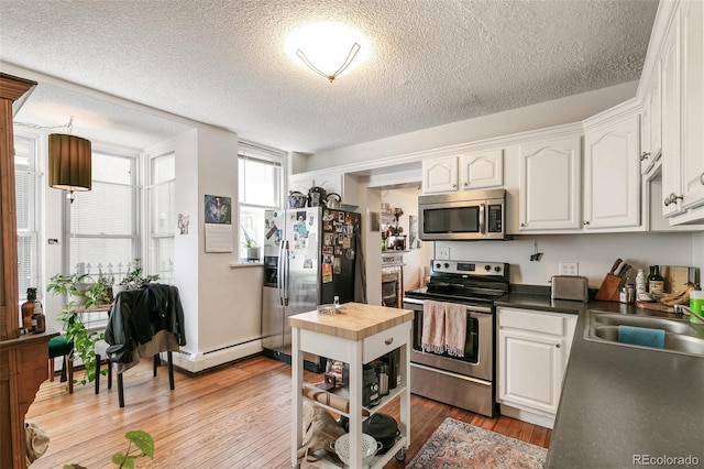 kitchen featuring appliances with stainless steel finishes, light hardwood / wood-style flooring, and white cabinets