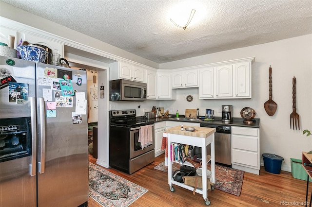 kitchen with white cabinetry, stainless steel appliances, a textured ceiling, and dark hardwood / wood-style flooring