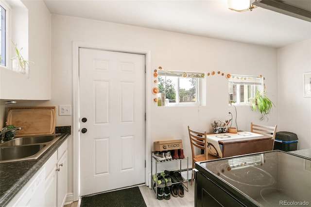 kitchen featuring sink, dishwasher, light hardwood / wood-style floors, white cabinets, and range with electric stovetop