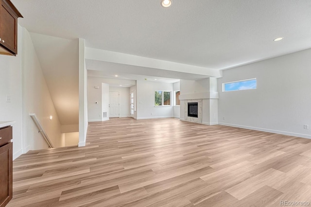 unfurnished living room featuring a premium fireplace and light hardwood / wood-style flooring