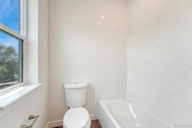 bathroom featuring a bathtub, hardwood / wood-style floors, and toilet