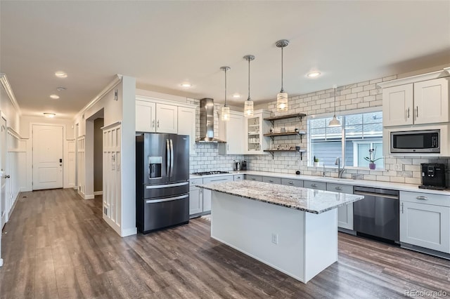 kitchen featuring white cabinets, a kitchen island, stainless steel appliances, and wall chimney range hood