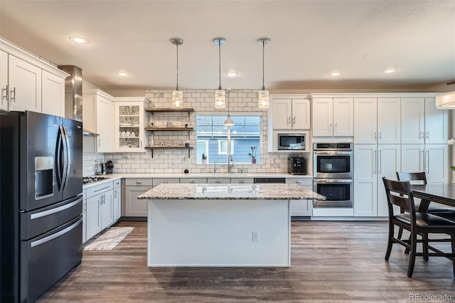 kitchen featuring appliances with stainless steel finishes, white cabinetry, hanging light fixtures, and a kitchen island