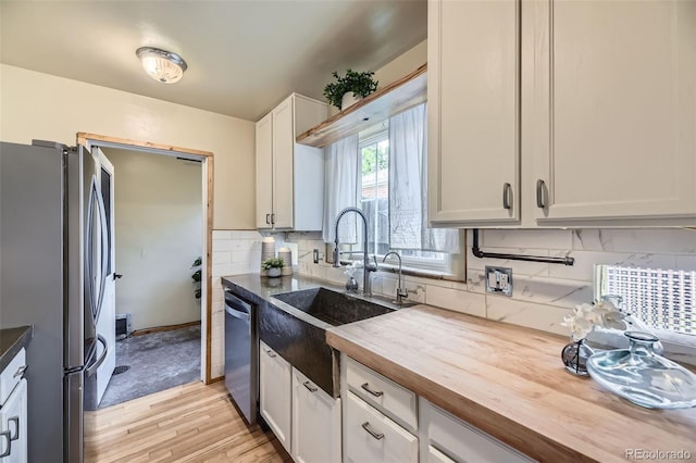 1292 Kearney St, Denver, CO 80220 - kitchen with appliances with stainless steel finishes, wooden counters, a sink, backsplash, and light wood-style flooring