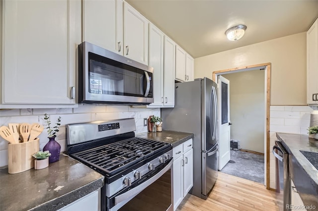 1292 Kearney St, Denver, CO 80220 - kitchen with appliances with stainless steel finishes, white cabinetry, decorative backsplash, and light wood-type flooring