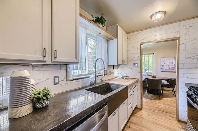 1292 Kearney St, Denver, CO 80220 - kitchen with appliances with stainless steel finishes, a sink, dark stone countertops, light wood-type flooring, and decorative backsplash