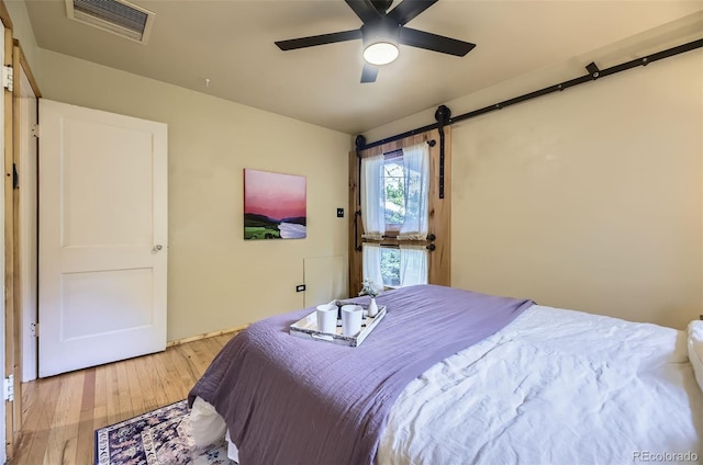 1292 Kearney St, Denver, CO 80220 - bedroom with light wood-style flooring, a barn door, and ceiling fan