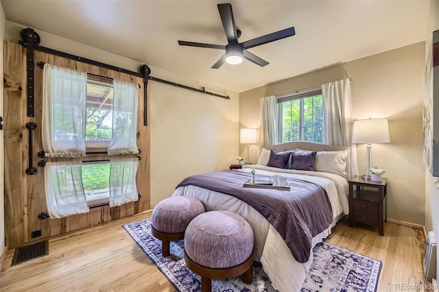 1292 Kearney St, Denver, CO 80220 - bedroom with a barn door, light wood-style floors, ceiling fan, and baseboard heating