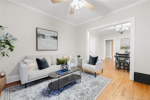 living room featuring baseboards, ceiling fan with notable chandelier, light wood-style flooring, and crown molding