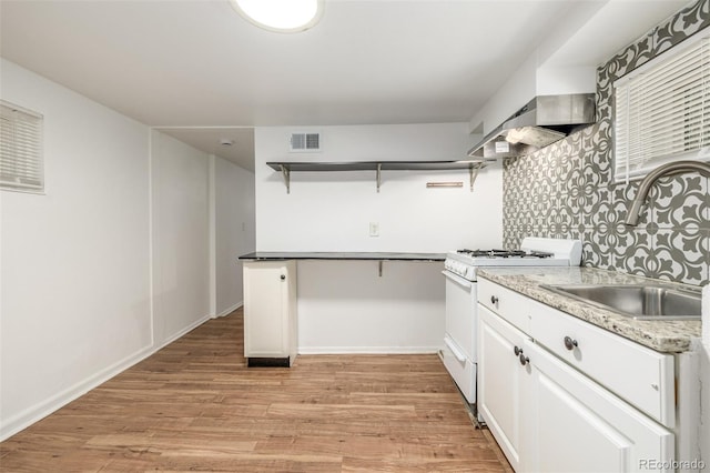 kitchen featuring visible vents, white range with gas cooktop, open shelves, a sink, and light wood finished floors