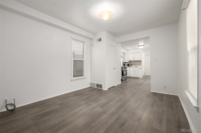 unfurnished living room featuring dark wood finished floors, visible vents, and baseboards