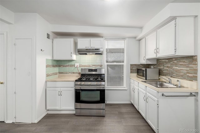 kitchen with a sink, under cabinet range hood, white cabinetry, appliances with stainless steel finishes, and light countertops