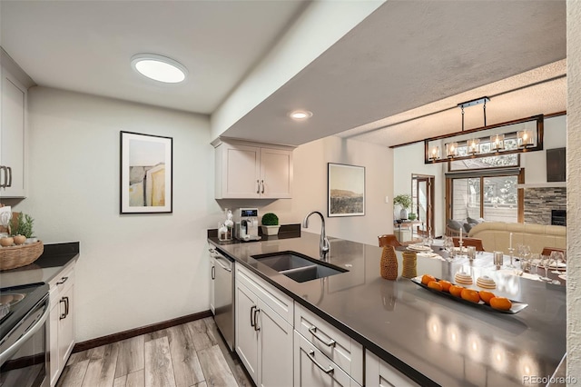 kitchen featuring a peninsula, dark countertops, light wood-type flooring, a sink, and stainless steel appliances