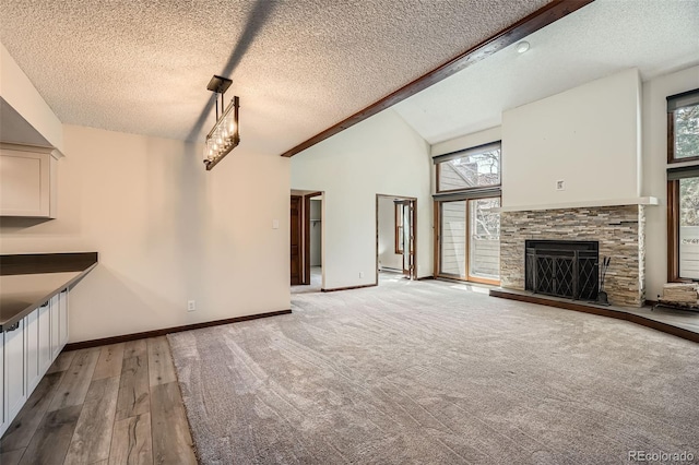 unfurnished living room featuring a textured ceiling, a stone fireplace, light wood finished floors, and high vaulted ceiling