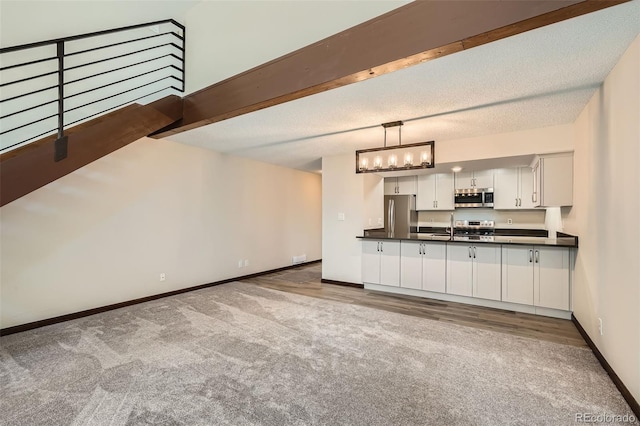 kitchen featuring carpet flooring, a sink, appliances with stainless steel finishes, and dark countertops
