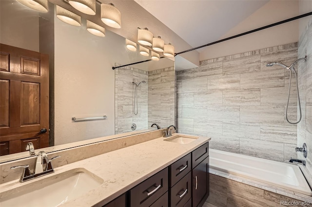 bathroom with a sink, tiled shower / bath, and vaulted ceiling