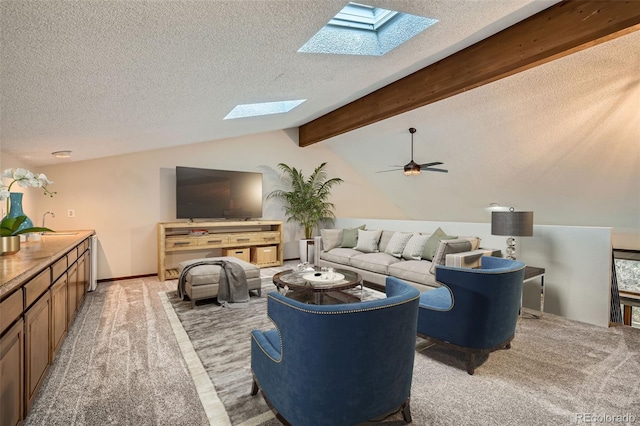 living room with a textured ceiling, light carpet, ceiling fan, and vaulted ceiling with skylight