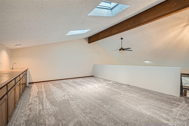 additional living space featuring ceiling fan, light colored carpet, a sink, a textured ceiling, and lofted ceiling with skylight