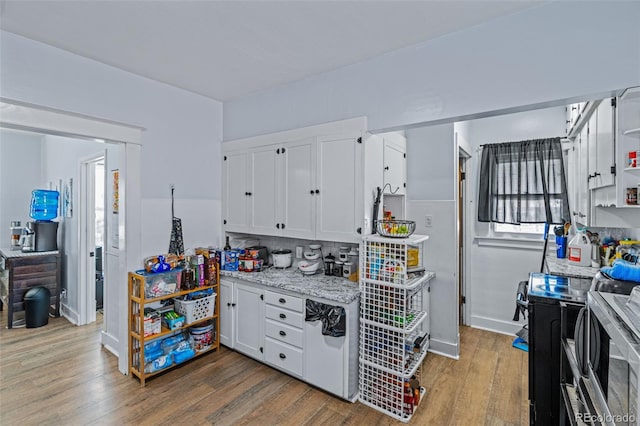 kitchen featuring open shelves, white cabinets, light wood finished floors, decorative backsplash, and light stone countertops