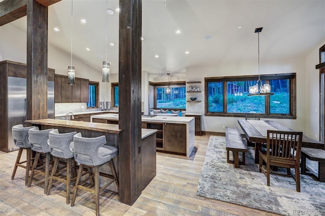 141 Sawmill Run Dr, Breckenridge, CO 80424 - kitchen with a large island with sink, light wood-style floors, dark brown cabinetry, light countertops, and lofted ceiling
