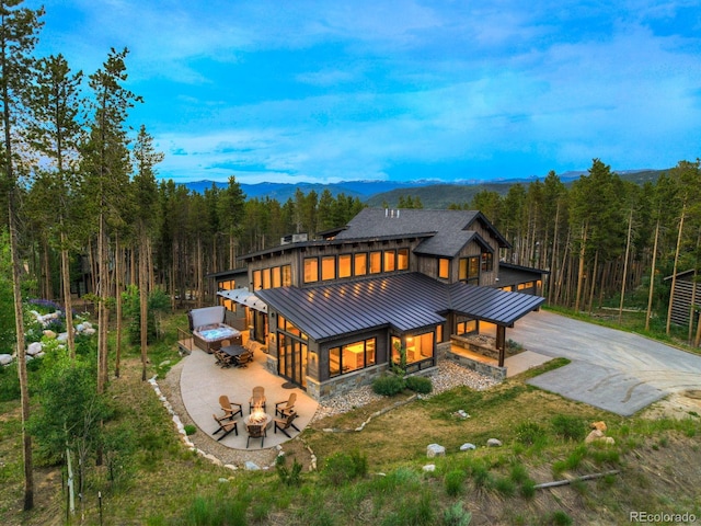 141 Sawmill Run Dr, Breckenridge, CO 80424 - rear view of property featuring a standing seam roof, a forest view, a fire pit, driveway, and a metal roof