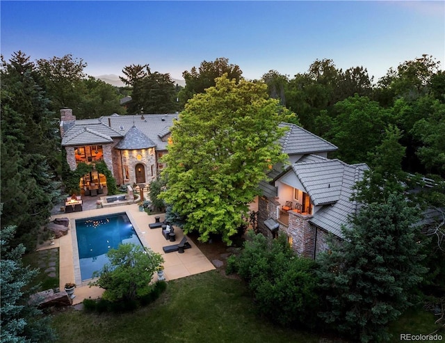 850 E Radcliff Ave, Cherry Hills Village, CO 80113 - rear view of house featuring stone siding, a patio area, an outdoor pool, and a chimney