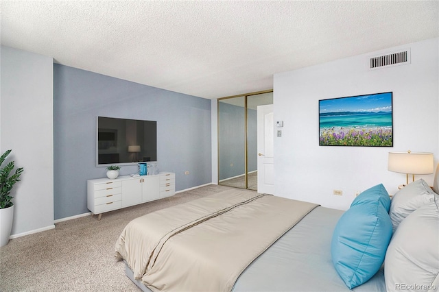 carpeted bedroom with a closet, visible vents, a textured ceiling, and baseboards