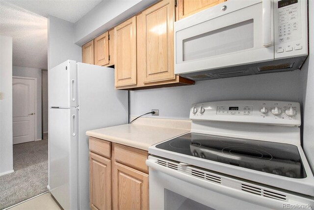 kitchen featuring carpet flooring, white appliances, light countertops, and light brown cabinets