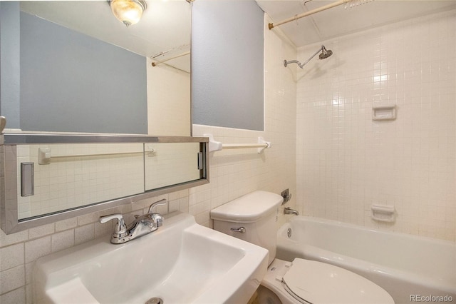 bathroom with washtub / shower combination, a sink, tile walls, and toilet