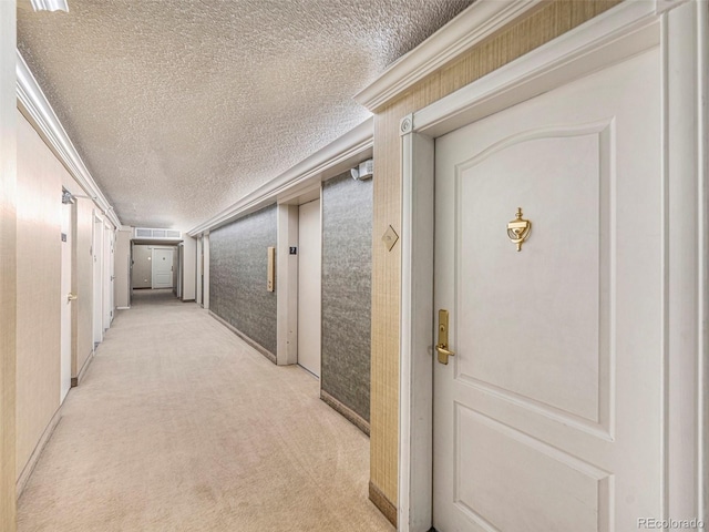 corridor featuring a textured ceiling and light colored carpet