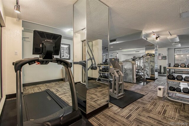 gym with a textured ceiling, carpet, visible vents, and baseboards