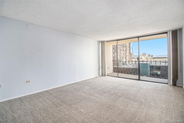 empty room featuring baseboards, a textured ceiling, a city view, carpet flooring, and floor to ceiling windows