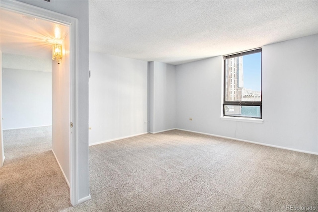 unfurnished room with light colored carpet, a textured ceiling, and baseboards