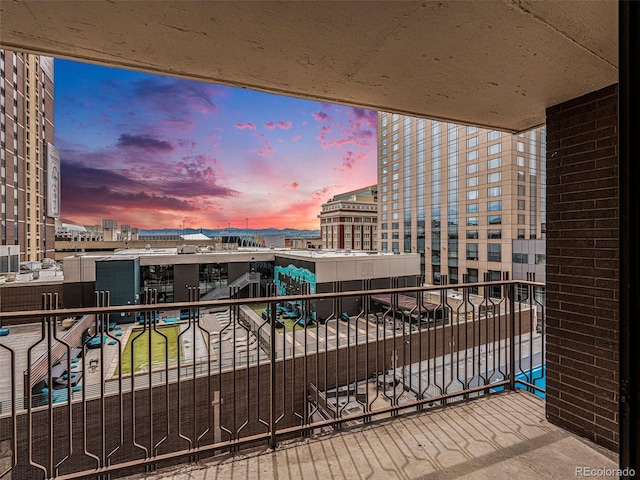 balcony at dusk featuring a city view