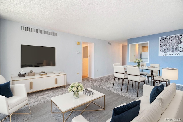 living room featuring a textured ceiling, visible vents, and light wood-style floors