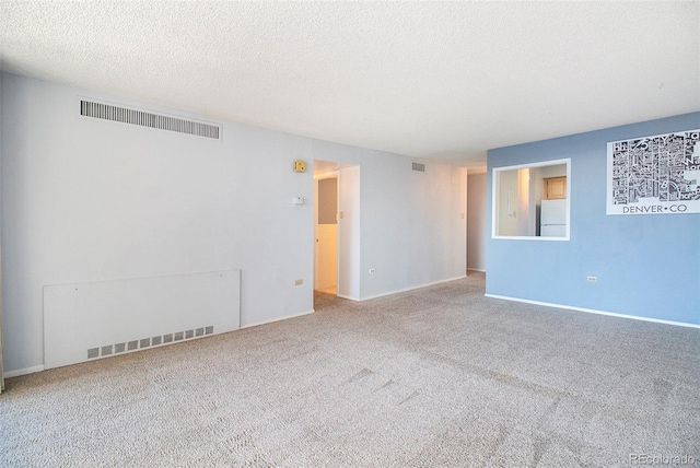 carpeted empty room featuring visible vents and a textured ceiling