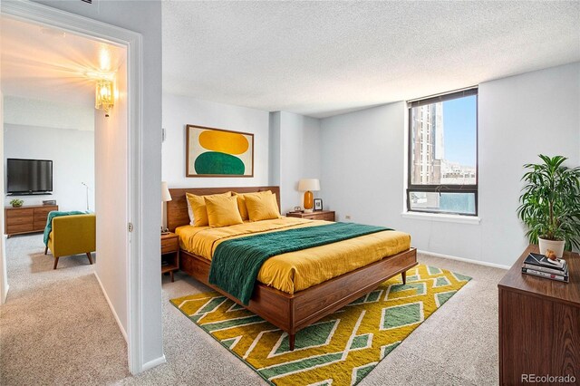 bedroom featuring light carpet, baseboards, and a textured ceiling