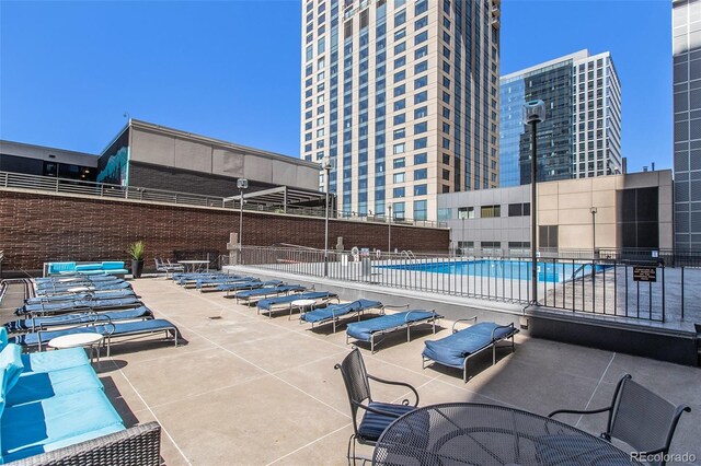 community pool featuring a view of city, a patio area, and fence