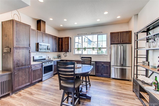 8361 Parkland St, Broomfield, CO 80021 - kitchen featuring stainless steel appliances, decorative backsplash, a sink, light wood-style floors, and dark brown cabinetry