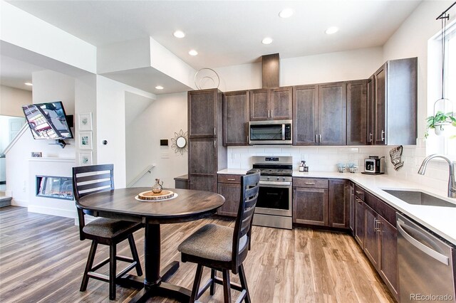 8361 Parkland St, Broomfield, CO 80021 - kitchen with dark brown cabinetry, light wood-style flooring, a sink, and appliances with stainless steel finishes
