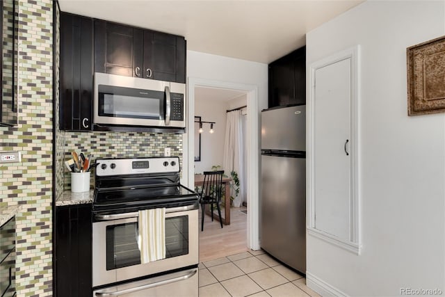 kitchen with light stone counters, appliances with stainless steel finishes, light tile patterned floors, and decorative backsplash