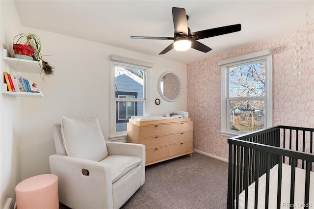 carpeted bedroom featuring ceiling fan and a nursery area