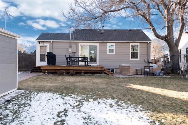 snow covered back of property with a wooden deck and a lawn