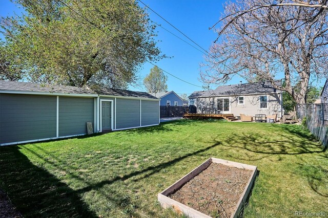 4920 Clay St, Denver, CO 80221 - view of yard featuring an outdoor structure, a deck, a garden, and a fenced backyard