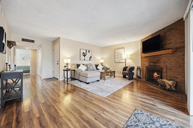 living room with hardwood / wood-style flooring, a brick fireplace, and a textured ceiling