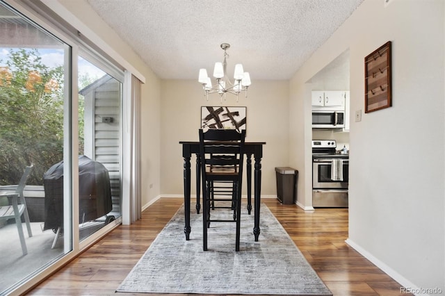 dining area with a textured ceiling, dark hardwood / wood-style floors, and a chandelier