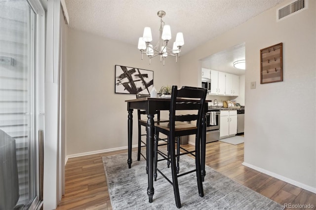 dining room featuring a chandelier, hardwood / wood-style floors, and a textured ceiling