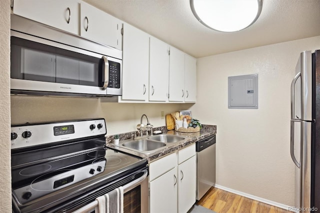 kitchen featuring sink, white cabinetry, light hardwood / wood-style flooring, appliances with stainless steel finishes, and electric panel